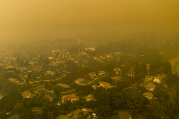 Smoky haze from wildfires over houses on winding streets and hillsides east of Los Angeles