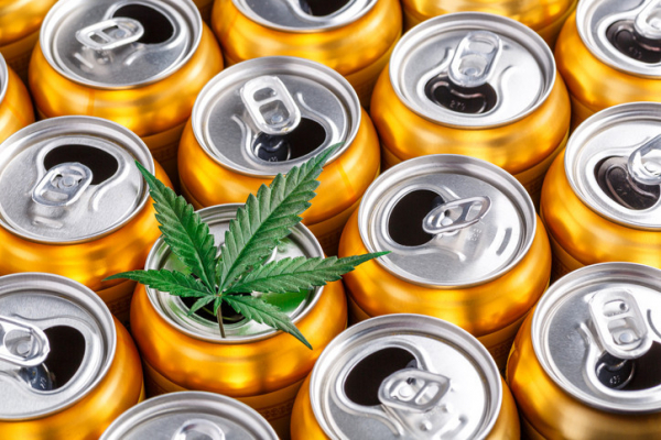 Group of golden aluminum cans with pull tab open and green marijuana leaf on top of one; concept is cannabis drinks 